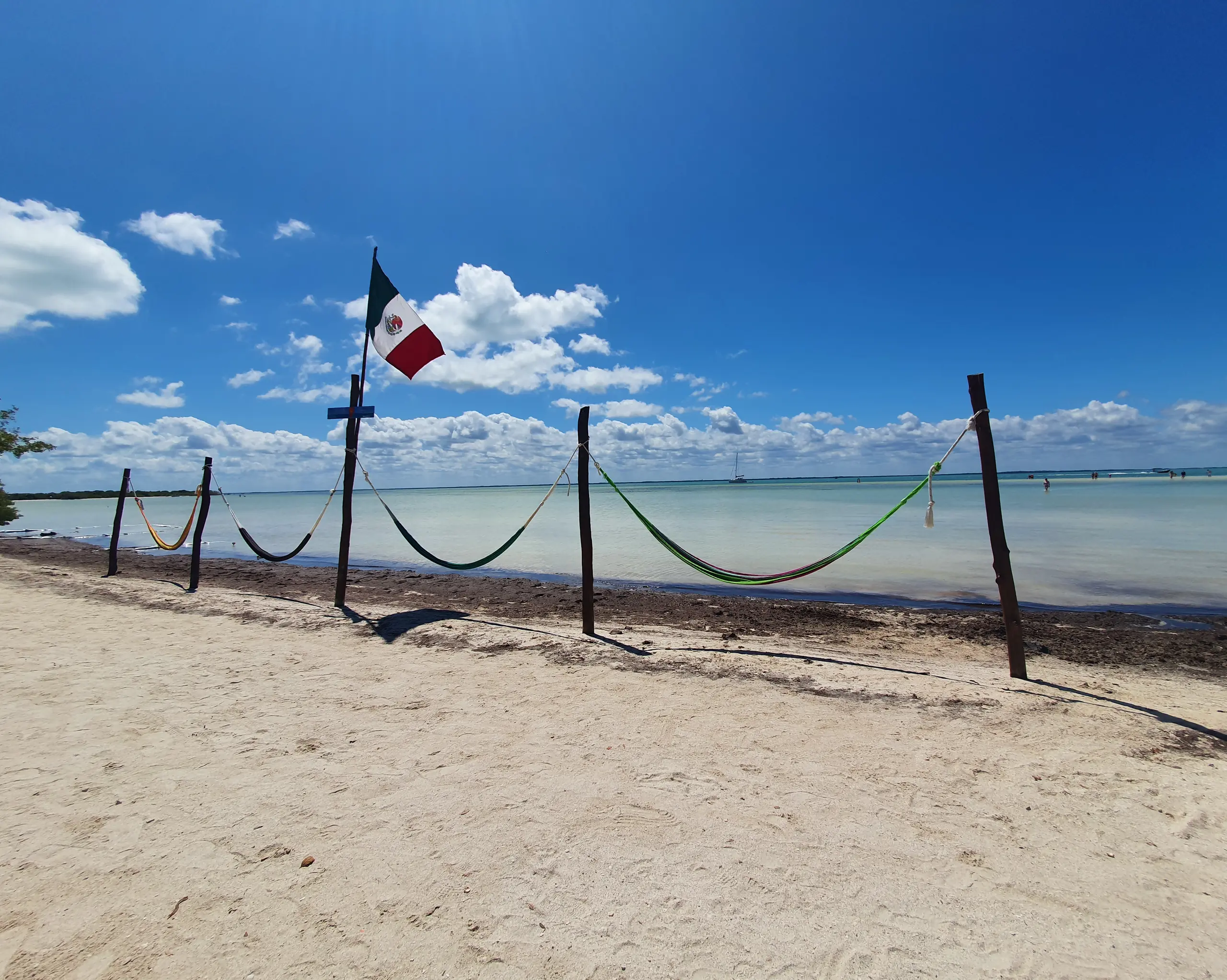 Hamacs et drapeau mexicain face à l'eau peu profonde sur une plage de Holbox